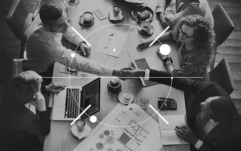 An overhead view of people shaking hands over a desk