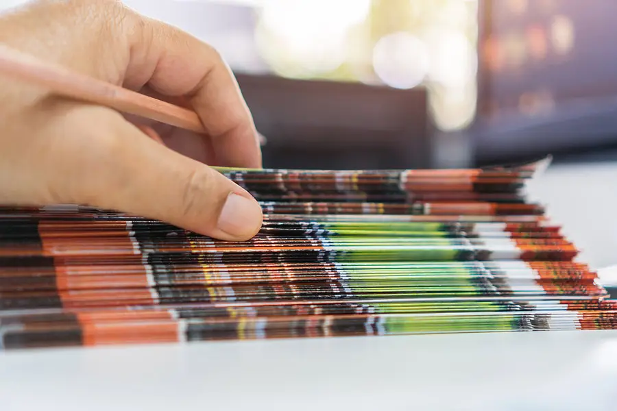 A closeup of a man's hand on a stack of color prints